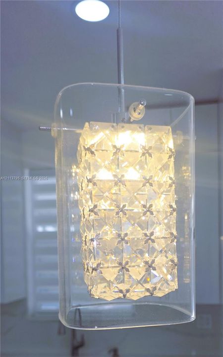 Contemporary pendant light featuring a rectangular clear glass outer shade, an interior multi-faceted textured crystal-style insert, and a metallic suspension rod