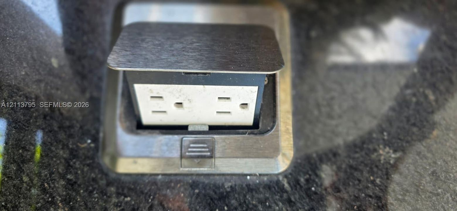 Countertop-mounted pop-up power outlet featuring a metallic finish
