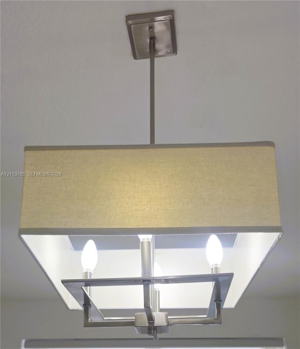 Satin-finish metal chandelier featuring a square fabric shade and three candelabra-style bulbs