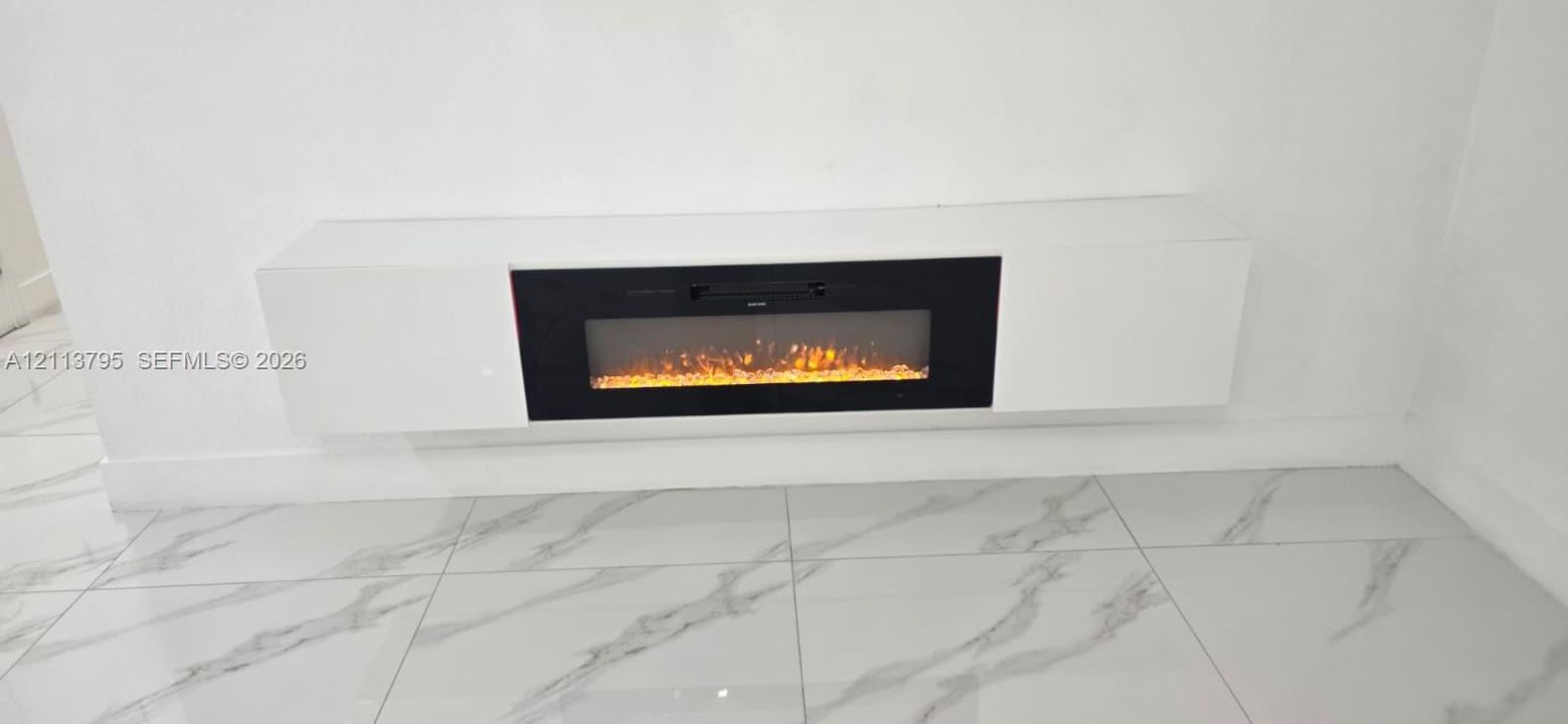 Wall-mounted electric fireplace featuring a high-gloss white surround and large-format rectified porcelain tile flooring