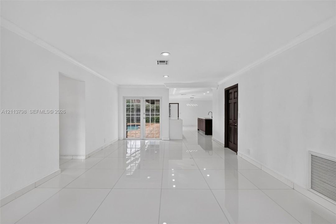 Open-concept room featuring large-format tile flooring, recessed lighting, and white-framed glass French doors