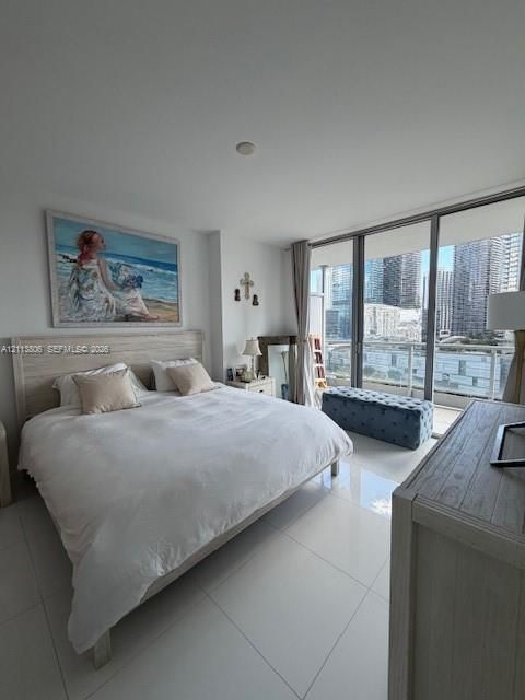 Floor-to-ceiling sliding glass doors, white tile flooring, and a private balcony