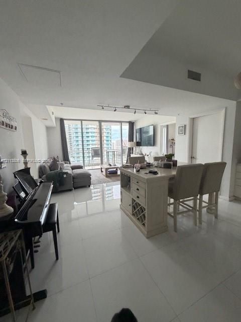 Open-concept interior featuring large-format tile flooring, floor-to-ceiling glass windows, and a built-in kitchen island with integrated wine storage and seating counter