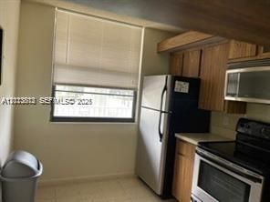 Kitchen featuring wood cabinetry, stainless steel appliances, and a window with horizontal blinds