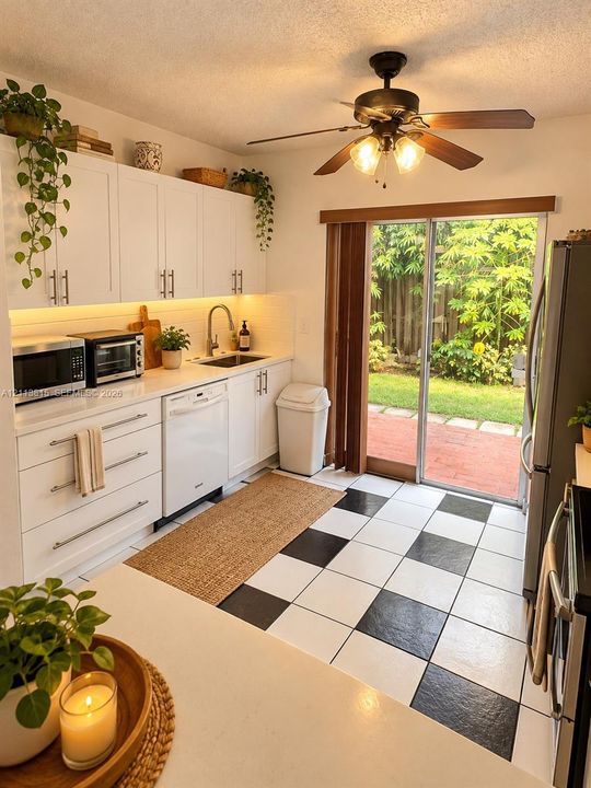 Kitchen featuring white Shaker-style cabinetry, quartz countertops, under-cabinet lighting, stainless steel sink with gooseneck faucet, and checkerboard tile flooring