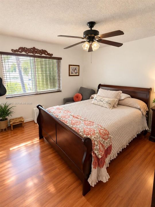 Wood-finish flooring, ceiling fan with integrated lighting, and horizontal window blinds with decorative wall-mounted trim