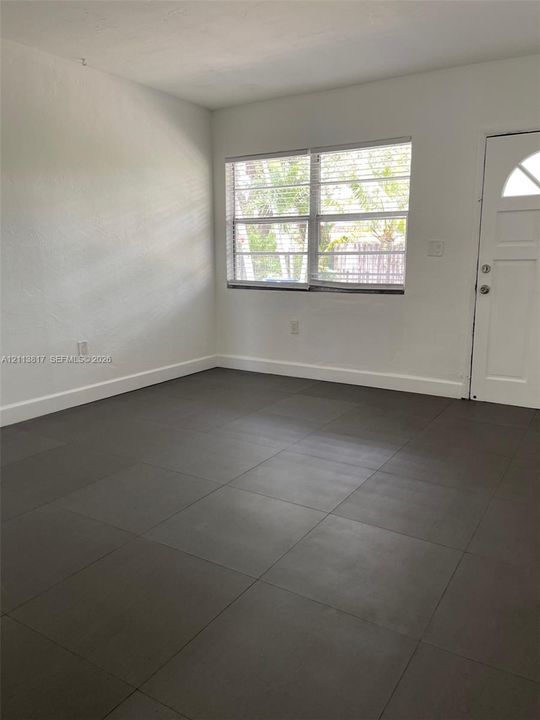 Neutral-toned tile flooring, white wall finish, multi-pane window, and exterior door with a crescent-shaped glass inset