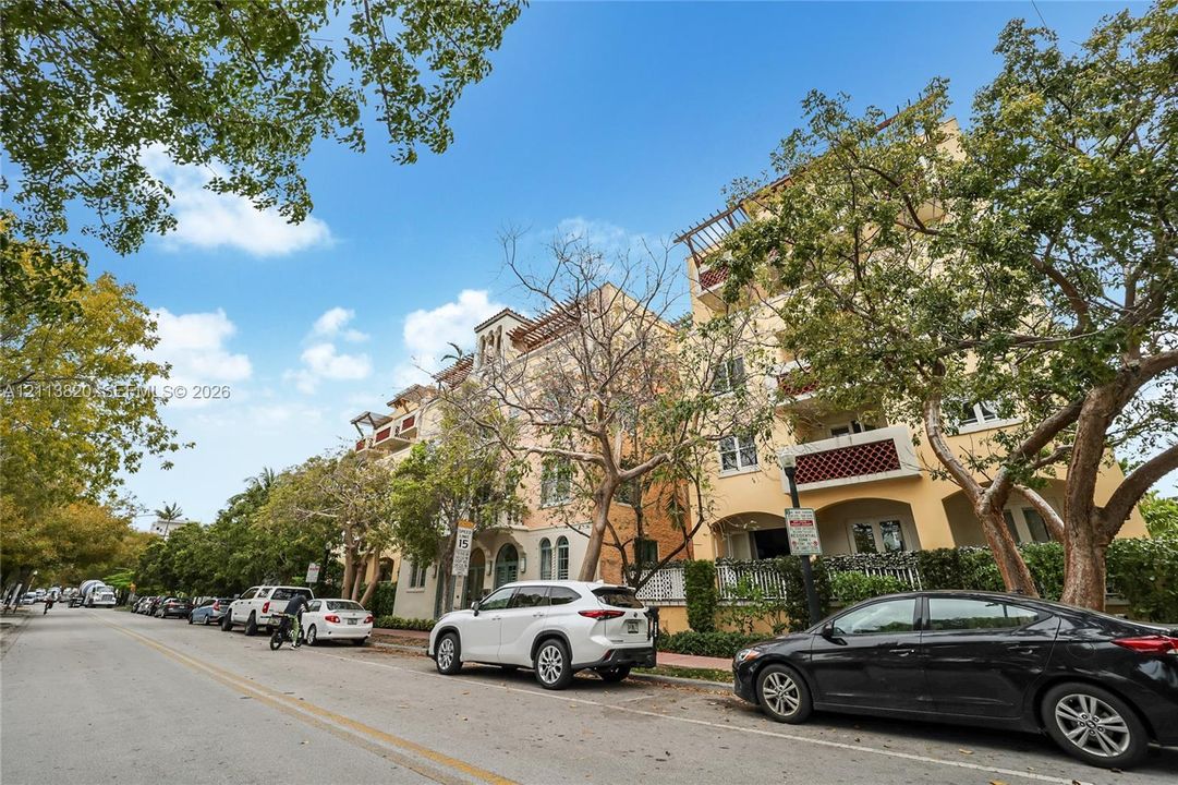 Multi-story exterior featuring a Mediterranean-inspired facade, arched architectural details, integrated balconies with metal railings, and rooftop pergolas