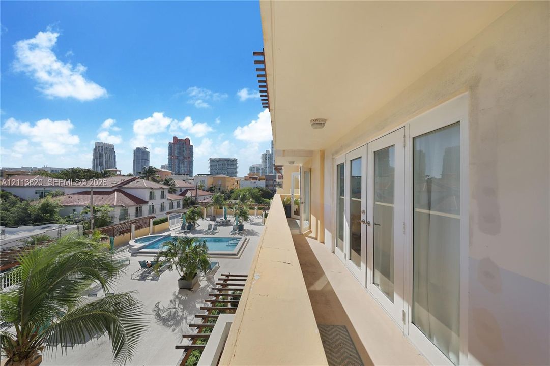 Covered outdoor balcony featuring glass-paneled double doors and metal railings