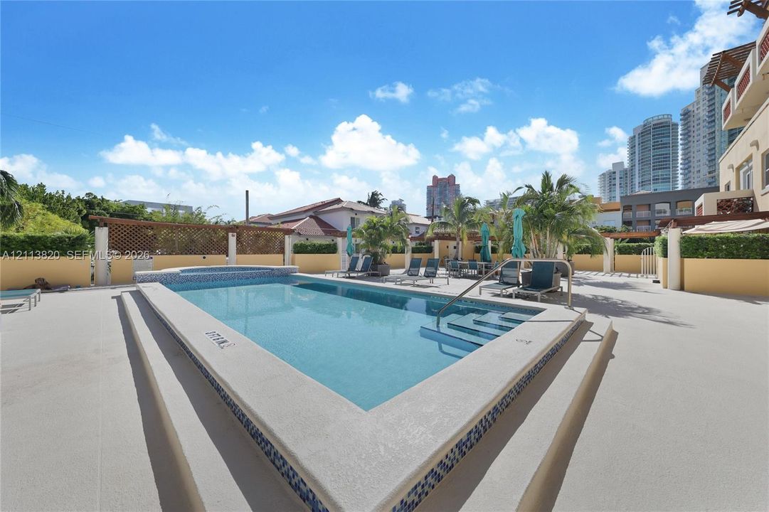 Rooftop pool featuring a raised spa, tile accents, integrated steps, and surrounding concrete deck space enclosed by privacy walls and trellis fencing