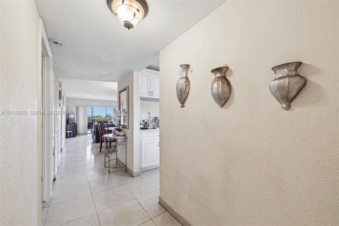 Neutral-toned interior featuring oversized tile flooring, semi-flush mount ceiling lighting, and crisp white cabinetry