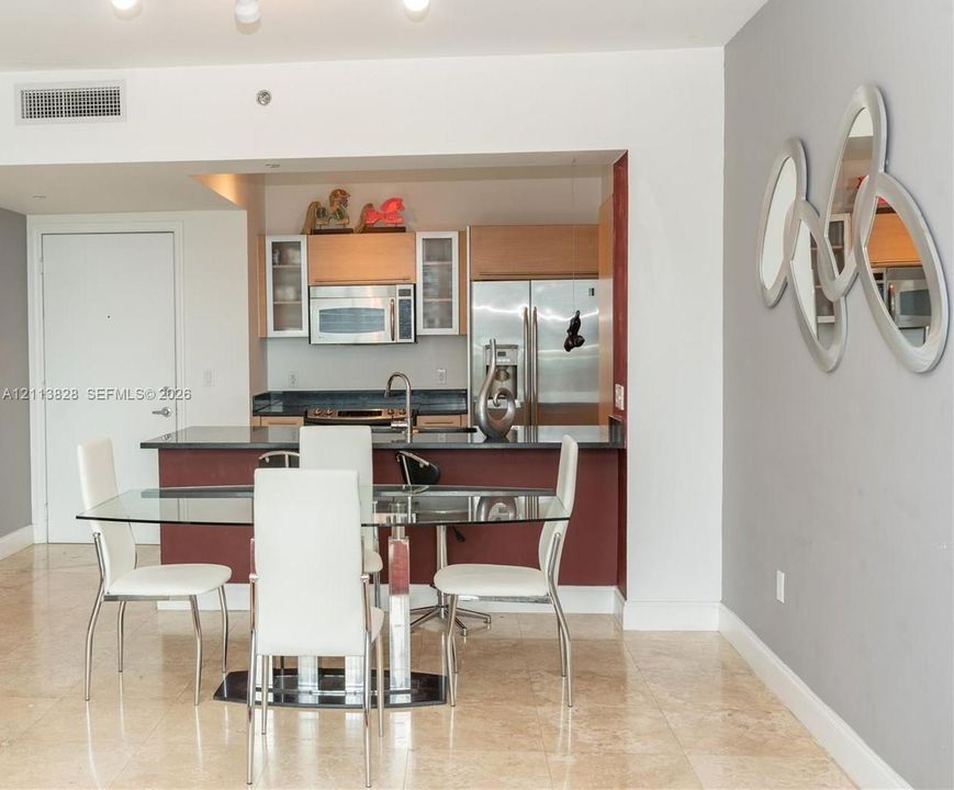 Kitchen featuring wood-finish cabinetry, stainless steel appliances, and dark stone countertops with an integrated breakfast bar