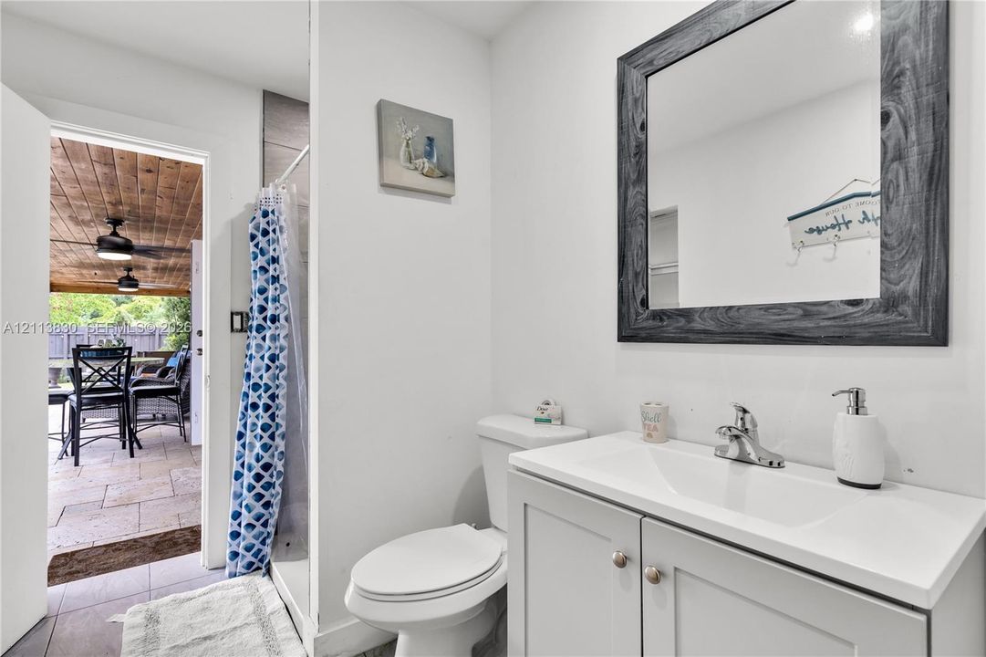 Bathroom featuring a gray shaker-style vanity with a white countertop and integrated sink, chrome faucet, and a wall-mounted mirror with a distressed gray wood-finish frame