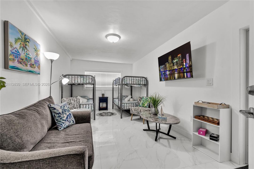 Spacious room featuring polished stone-finish tile flooring, clean white walls, and a recessed ceiling light fixture