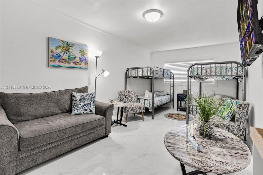 Large-format polished tile flooring, neutral wall tones, and recessed ceiling lighting with horizontal blinds
