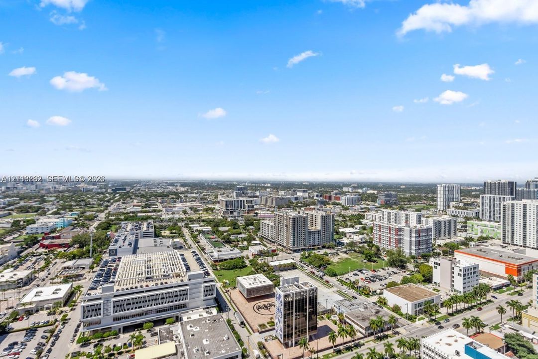 High-elevation aerial perspective of the surrounding metropolitan cityscape featuring dense commercial structures, multi-story residential buildings, and planned urban hardscaping