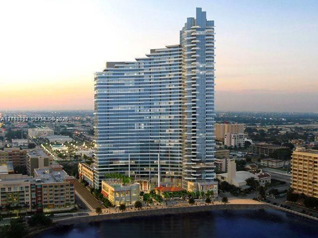 High-rise residential tower featuring a glass-curtain exterior, stepped architectural design, wrap-around balconies, and waterfront positioning