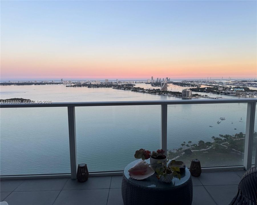 Covered balcony with a glass panel railing, showcasing expansive water and coastal city skylines