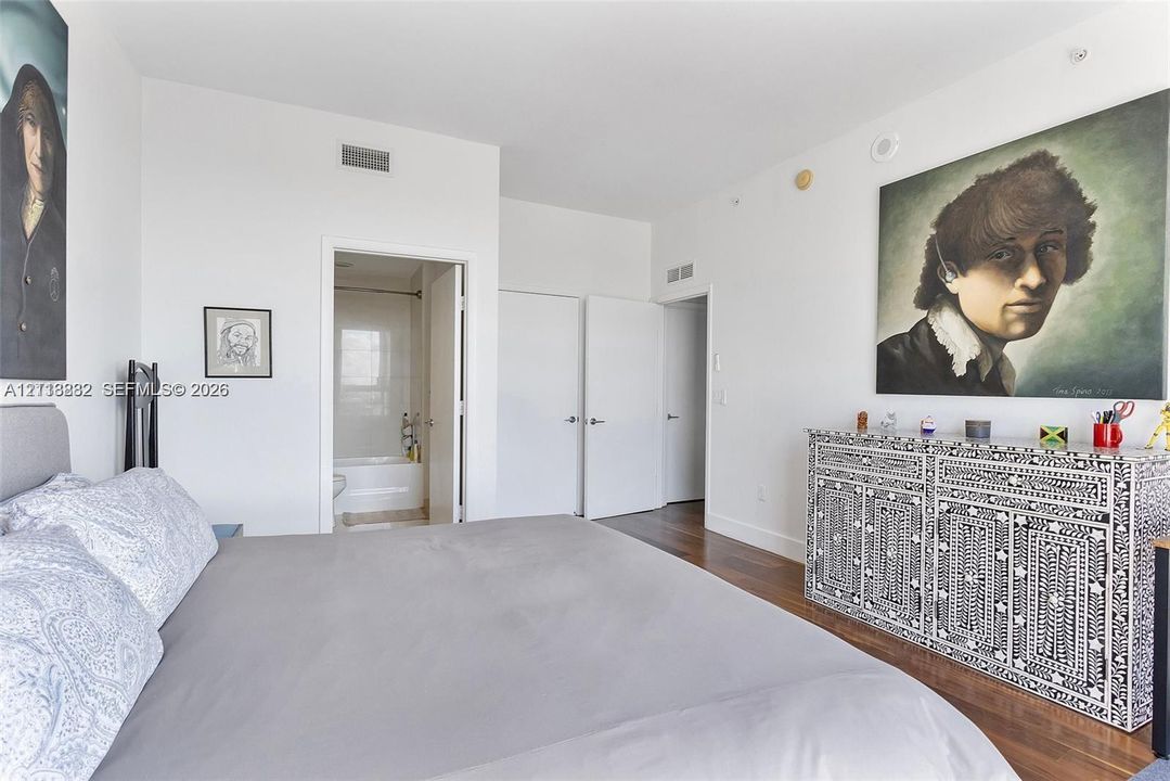 Bedroom featuring wood-finish flooring, white walls, and two sets of interior doors