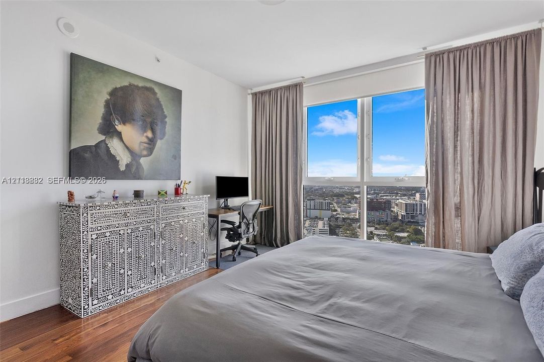 Floor-to-ceiling windows with panoramic urban backdrop and wood-finish flooring