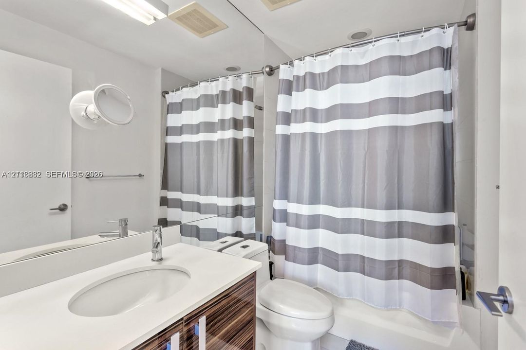 Bathroom featuring a wood-finish vanity cabinet, white countertop with an integrated sink, polished chrome faucet, and a full-width vanity mirror