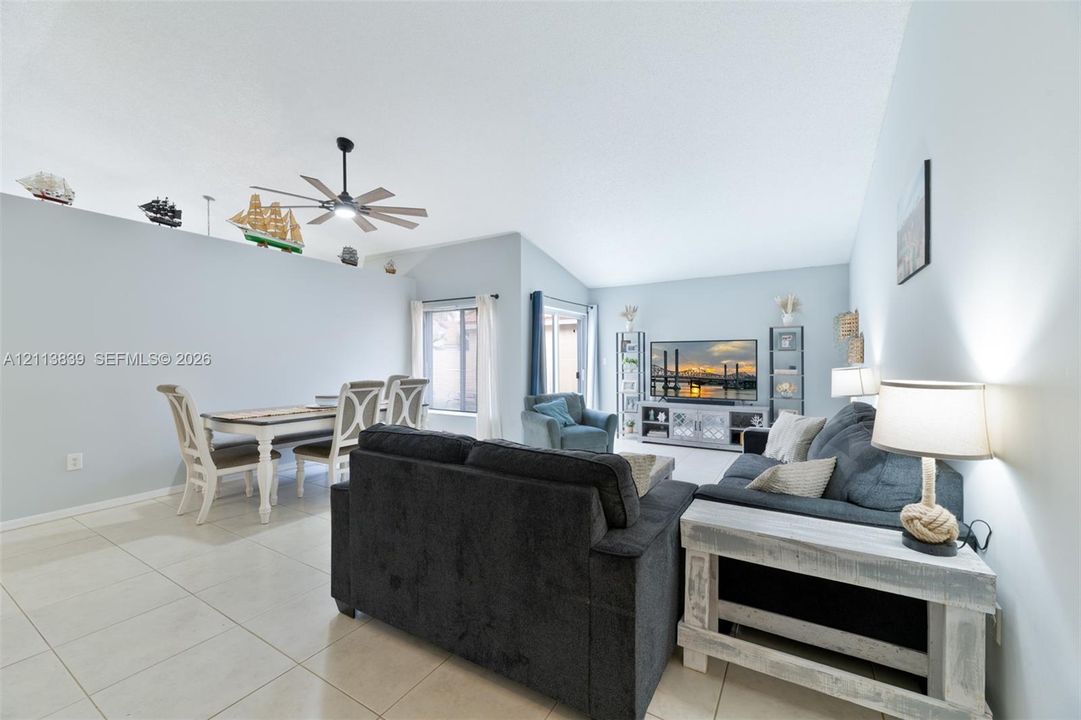 Vaulted ceilings, large-format tile flooring, ceiling fan, and sliding glass door
