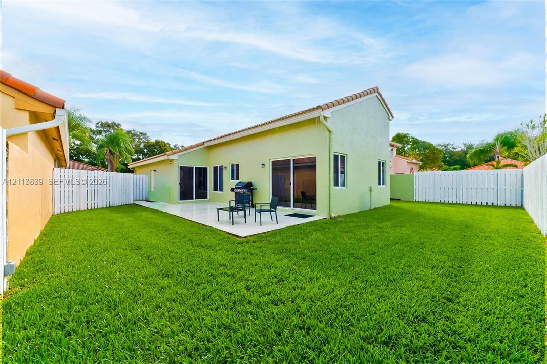 Backyard featuring a paved patio, perimeter privacy fencing, and a manicured lawn