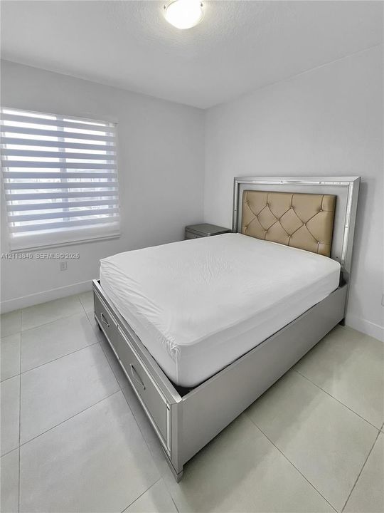 Large-format tile flooring, neutral walls, and dual-layered window blinds