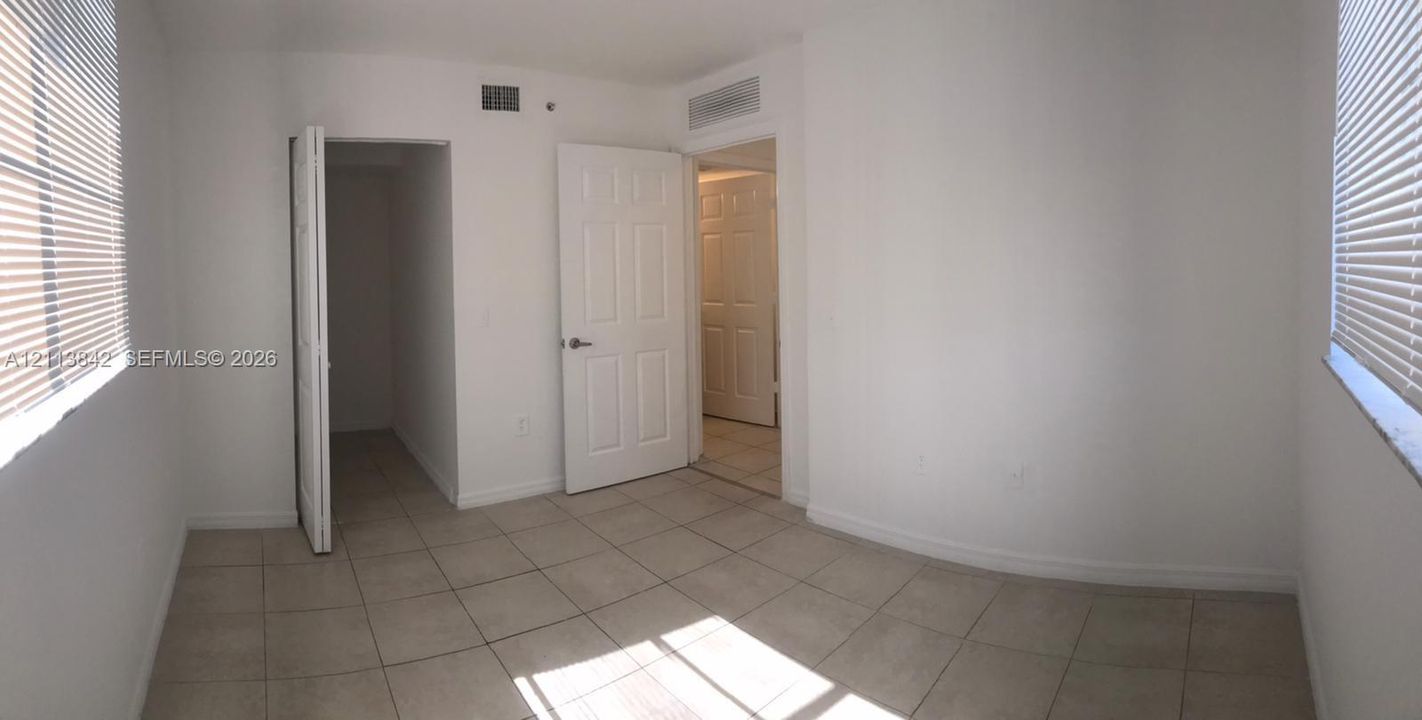 Neutral-toned tile flooring, dual windows with horizontal blinds, and paneled interior doors