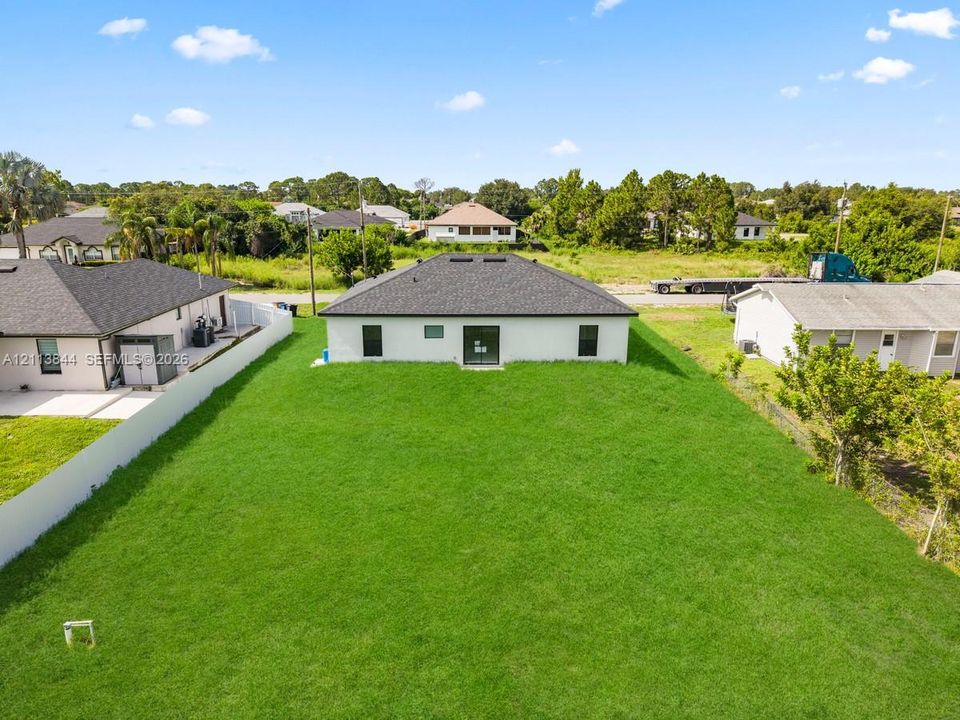 Expansive rear lawn with perimeter vinyl fencing and a dark-toned shingled hip roof