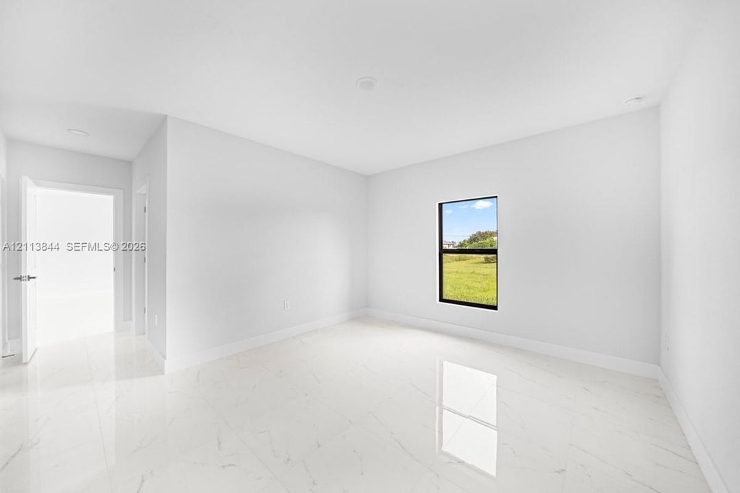 Interior space featuring large-format tile flooring, neutral wall paint, recessed lighting, and a single-pane window with black framing