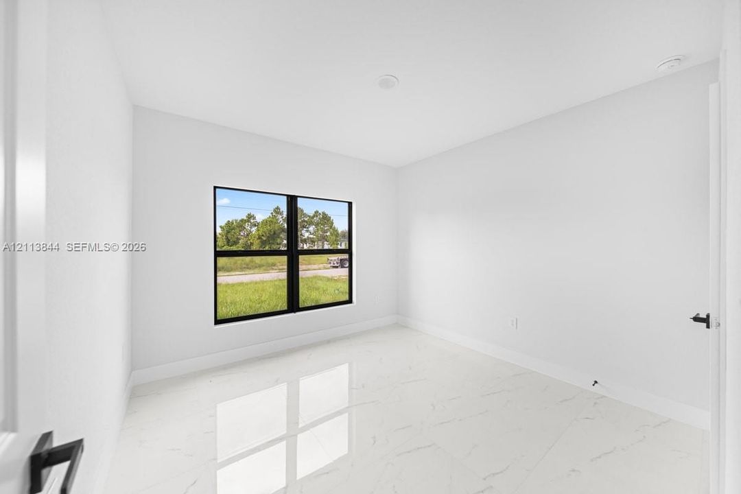Interior space featuring polished stone-finish tile flooring, neutral wall tones, recessed lighting, and a window with a black frame