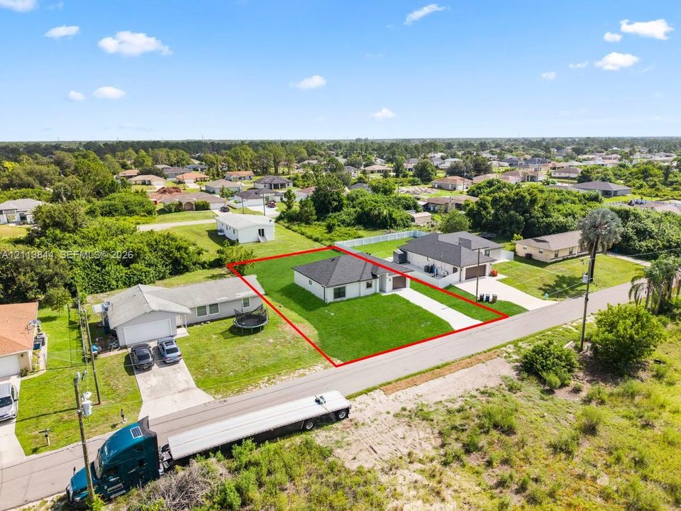 Single-story residence featuring a dark shingle roof, light-colored exterior finish, concrete driveway, and a maintained grass lawn