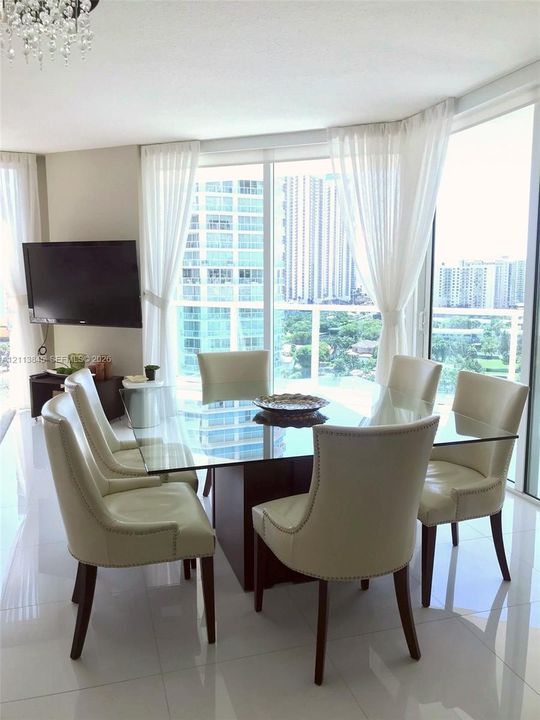 Floor-to-ceiling glass paneling, polished tile flooring, crystal chandelier, and wrap-around window configuration