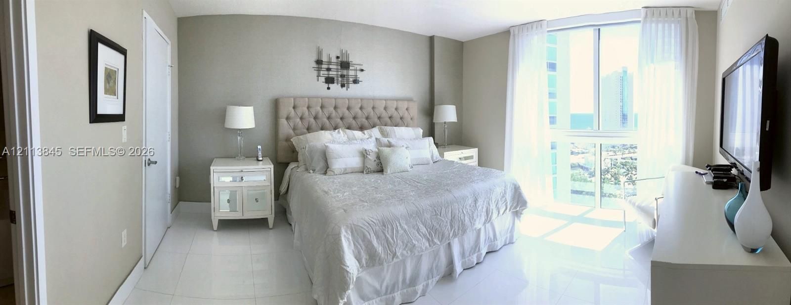 Floor-to-ceiling windows with neutral drapery, large-format tile flooring, and smooth-finish walls
