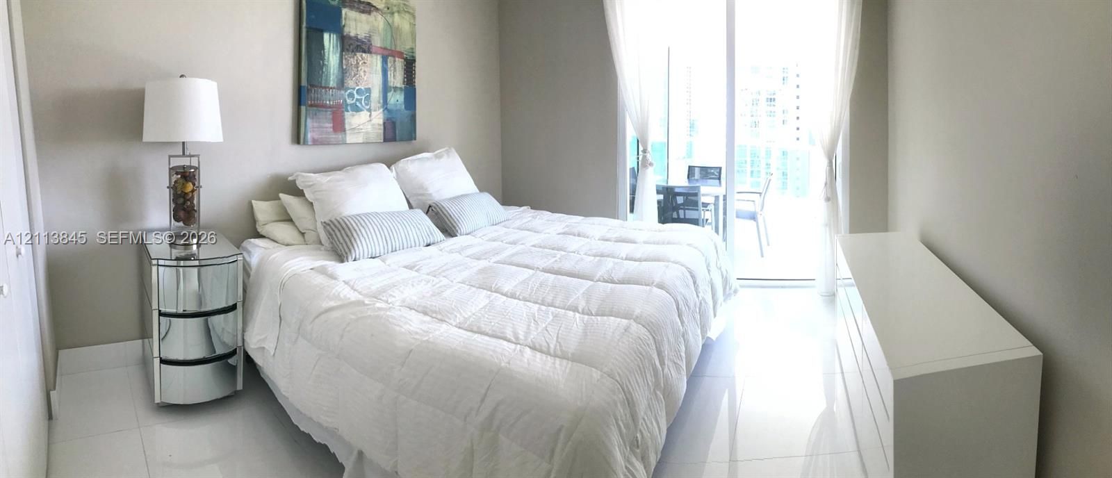 Spacious interior featuring white tile flooring, neutral wall tones, and glass sliding doors providing external access
