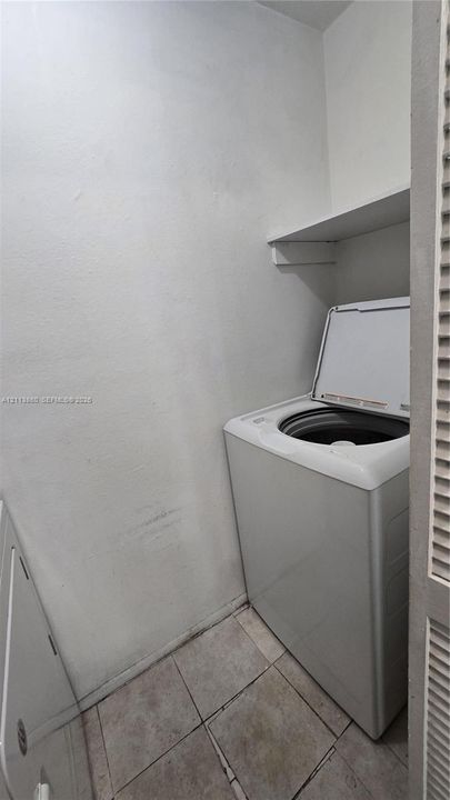 Laundry space featuring neutral tile flooring and built-in shelving