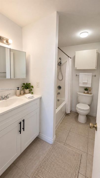 Bathroom featuring a white vanity cabinet with matte black hardware, integrated sink, mirrored medicine cabinet, neutral tile flooring, and a shower-tub combination
