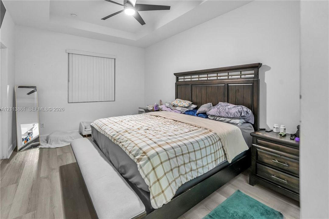 Tray ceiling, wood-finish flooring, and ceiling fan with integrated lighting