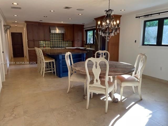 Kitchen featuring wood cabinetry, blue-painted center island with butcher-block countertop, recessed lighting, tile flooring, and a decorative chandelier