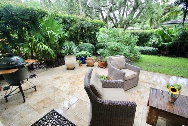 Stone paver patio featuring integrated landscaping with mature palm trees and manicured shrubbery