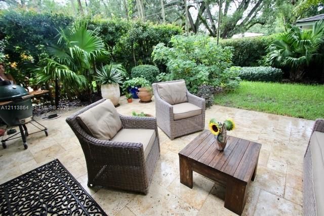 Stone paver patio featuring established perimeter landscaping, mature trees, and a grass lawn