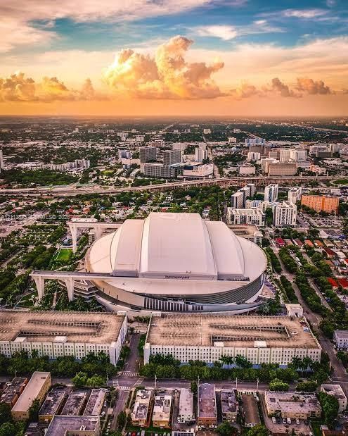 Aerial perspective featuring an urban landscape, prominent multi-level parking structures, and large-scale architectural development