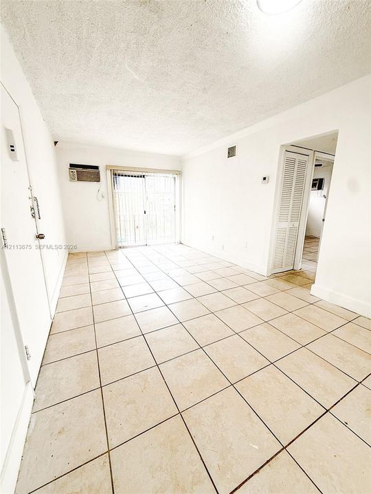 Light-filled interior featuring large-format ceramic tile flooring, sliding glass patio doors, and built-in closet with louvered doors