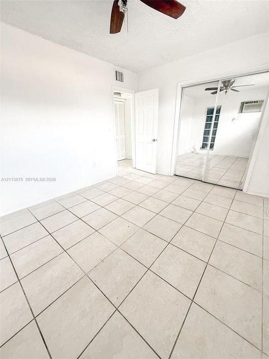 Ceramic tile flooring, mirrored sliding closet doors, and a ceiling fan