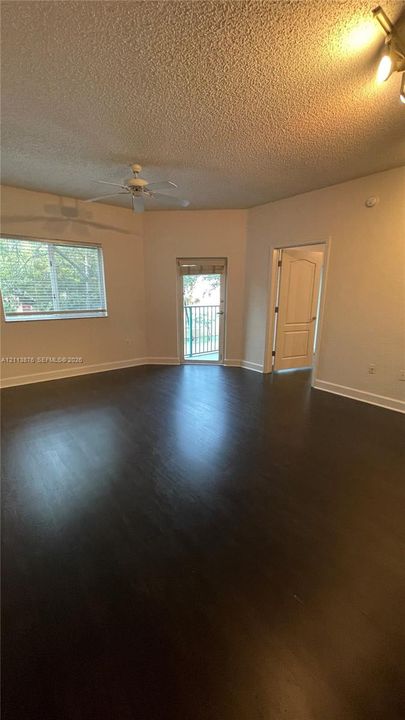 Interior space featuring wood-finish flooring, a ceiling fan, a glass-paneled exterior door, a multi-pane window, and a multi-panel interior door