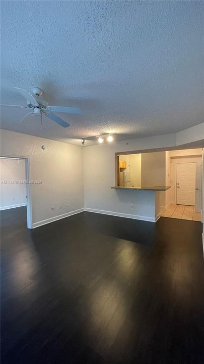 Dark wood-finish flooring, ceiling fan with light fixture, breakfast bar, and tile flooring at entryway