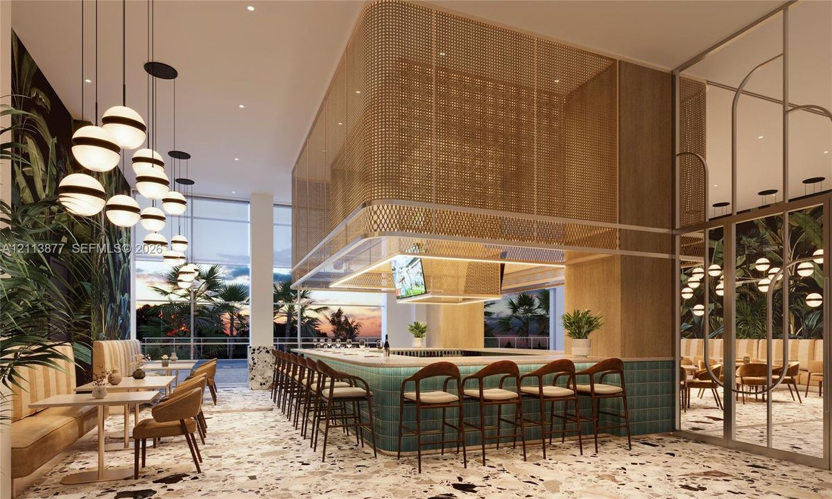 Central bar featuring a stone-topped counter with teal tile cladding, a suspended gold-tone metal mesh canopy, floor-to-ceiling glass paneling, terrazzo flooring, and spherical pendant lighting