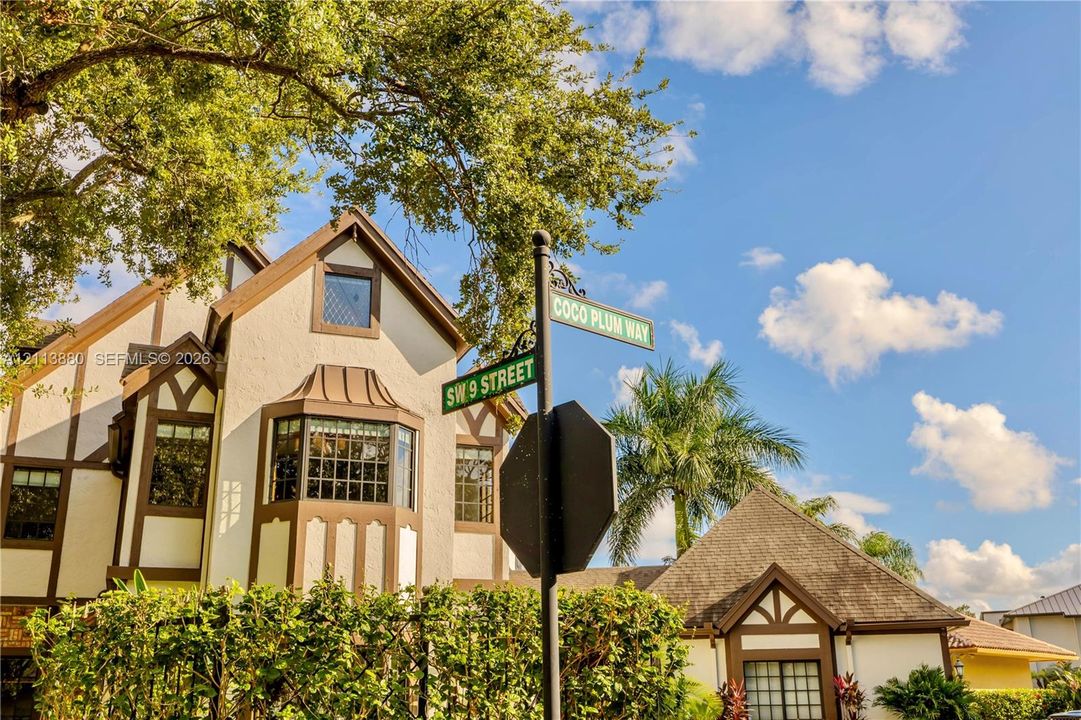 Tudor-style exterior featuring stucco facade with timber framing, multi-pane bay windows, and mature landscaping