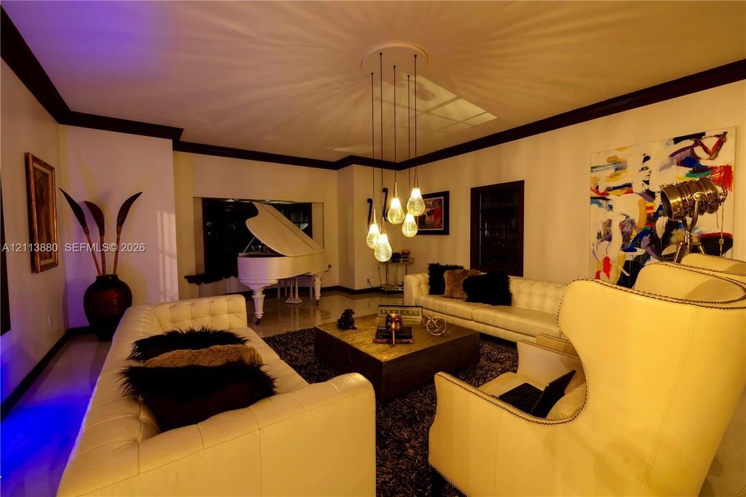 Living space featuring high ceilings, dark crown molding, polished flooring, and a multi-pendant glass light fixture